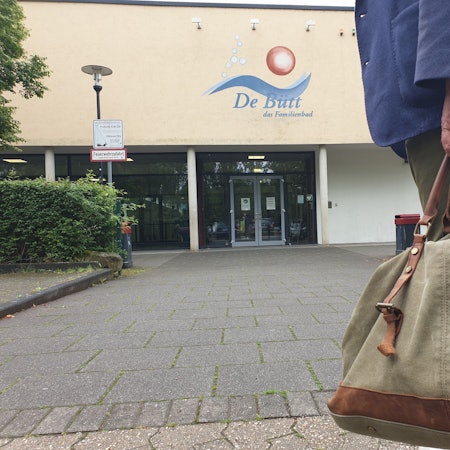 Ein Mann mit einer Sporttasche vor dem Eingang des Familienbads in Hürth.