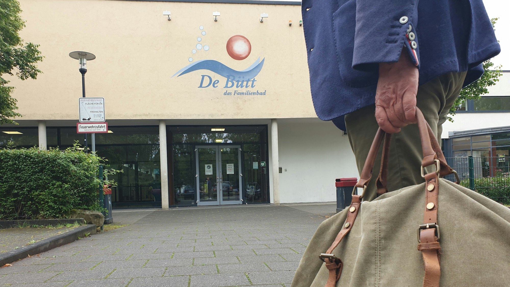 Ein Mann mit einer Sporttasche vor dem Eingang des Familienbads in Hürth.