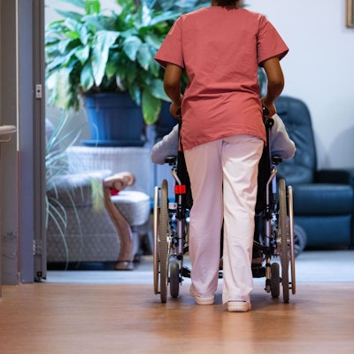 ARCHIV - 07.02.2024, Baden-Württemberg, Filderstadt: Eine Bewohnerin eines Pflegeheims wird von einer Pflegerin einen Gang entlang geschoben.