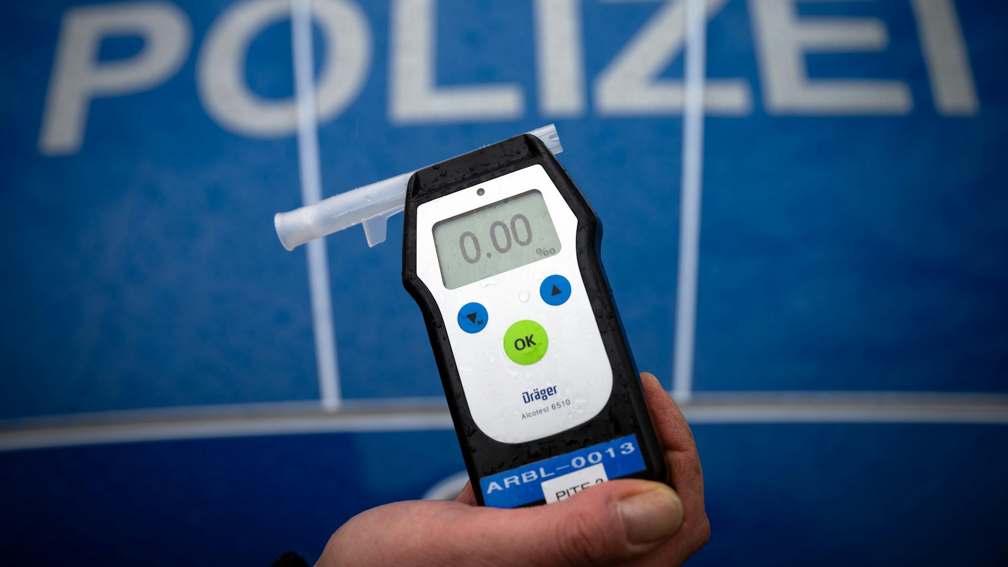 Ein Polizeibeamter hält ein Messgerät Alcotest, das den Alkoholwert von Null Promille anzeigt.