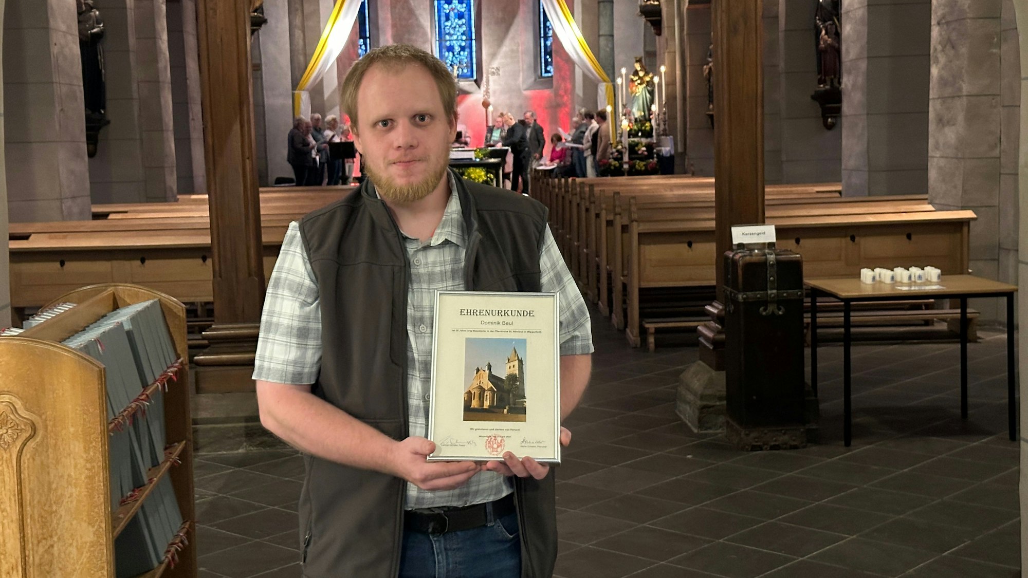 Foto von Dominik Beul in einem Kirchenraum – mit Urkunde in den Händen.