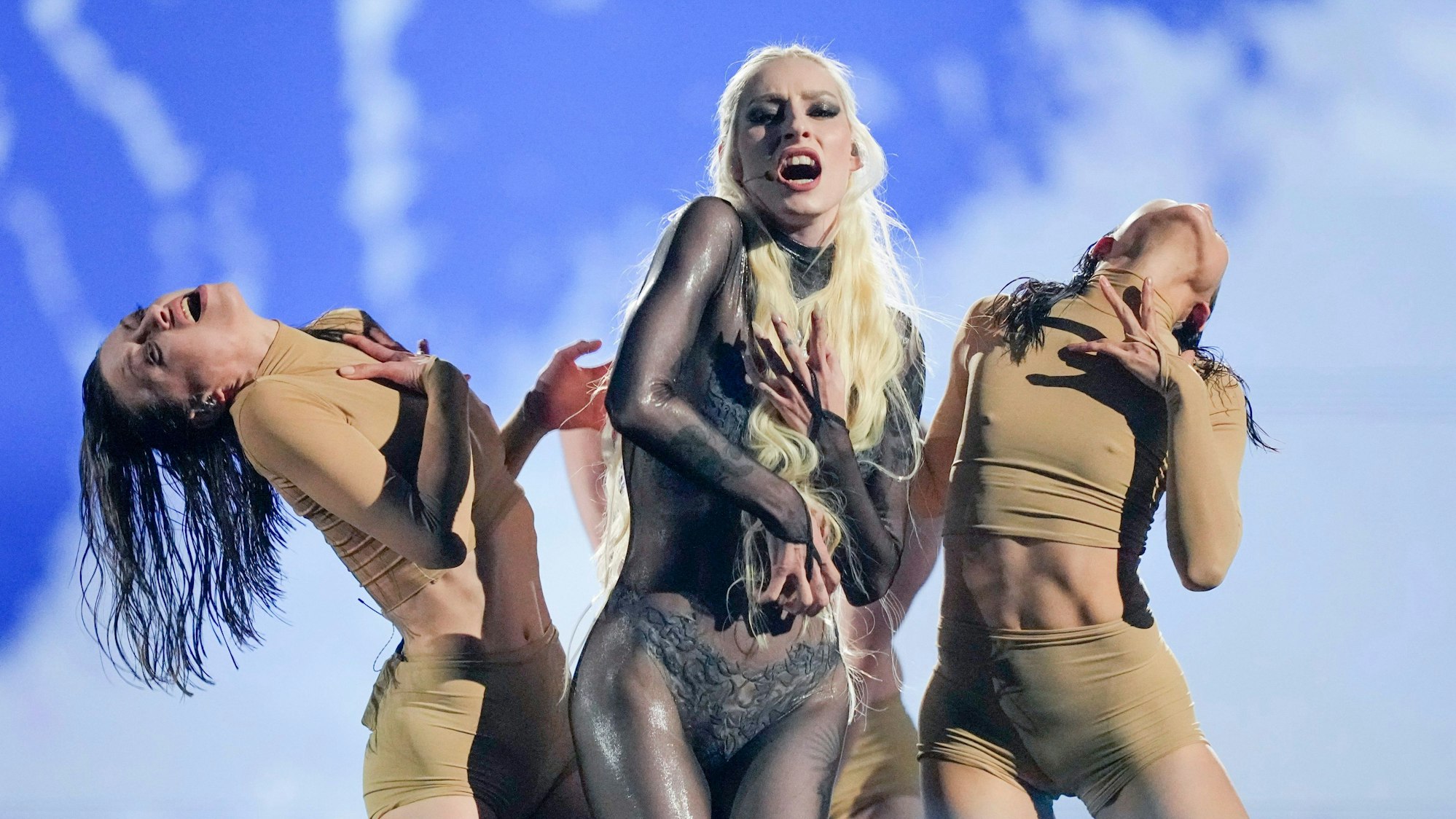 Raiven steht mit zwei Tänzerinnen auf der Bühne