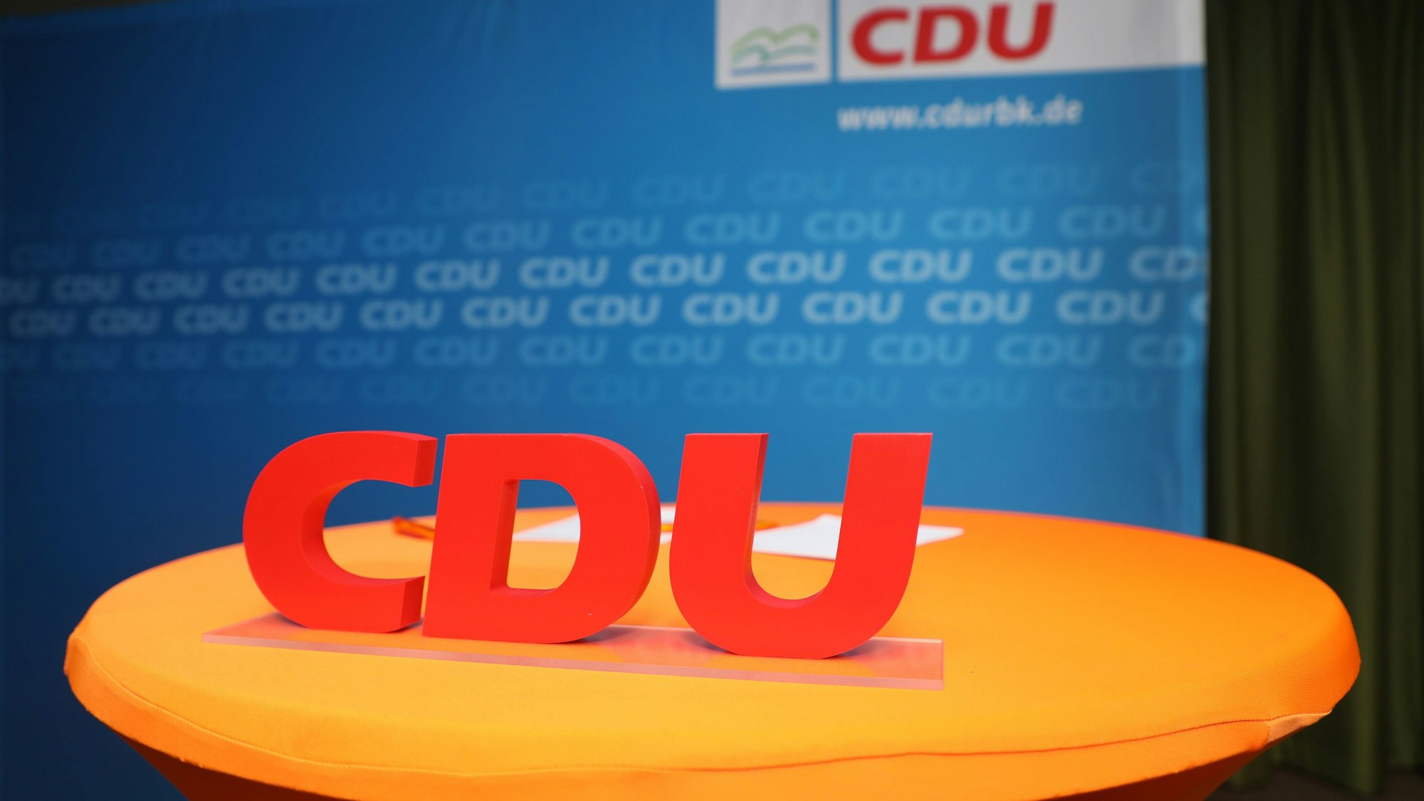 Ein CDU-Schriftzug steht vor eine Wan mit dem Schriftzug CDU RBK.