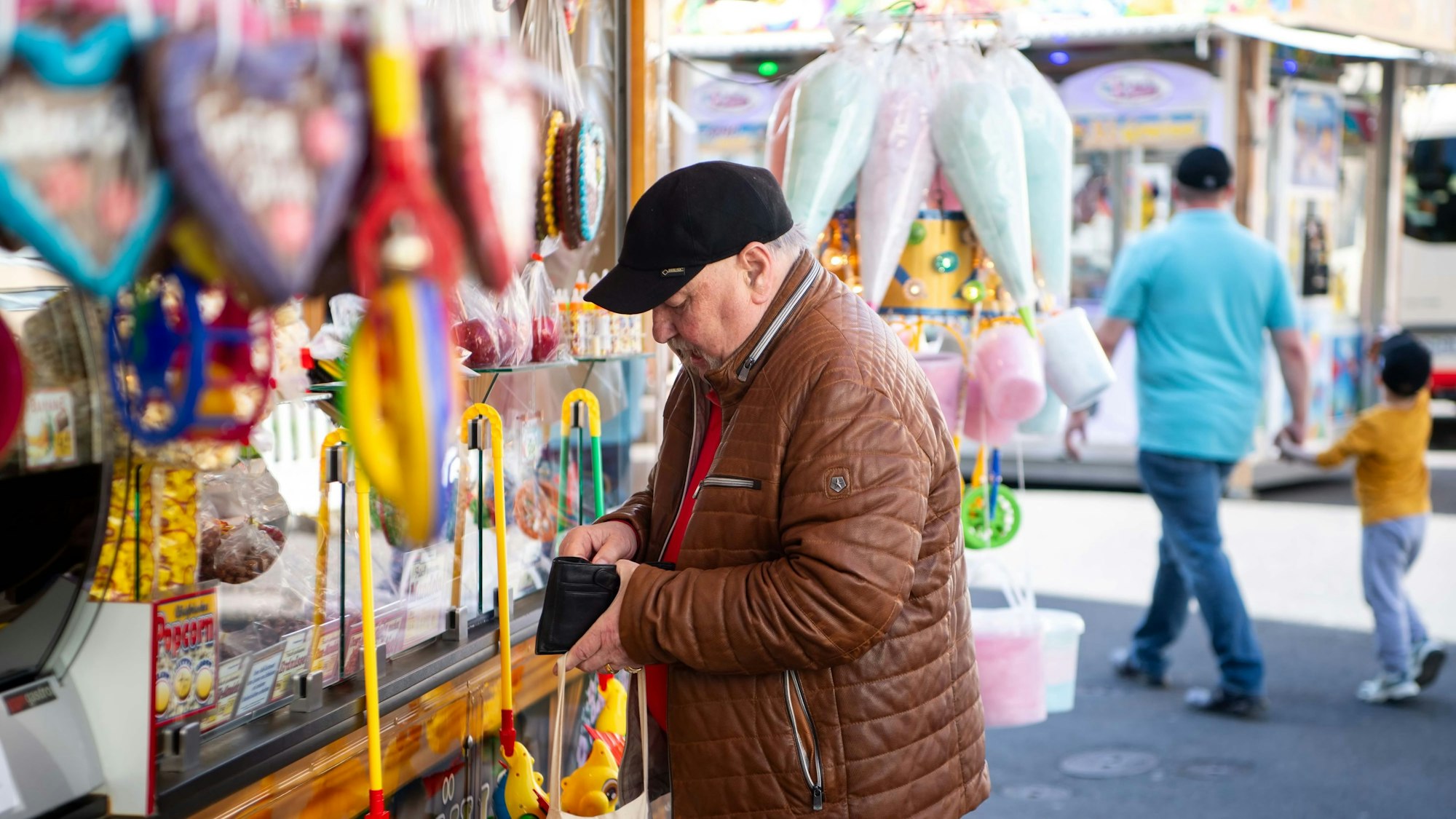 Das Bild zeigt einen Kirmesbesucher, der sich an einer Süßigkeitenbude etwas gekauft hat.