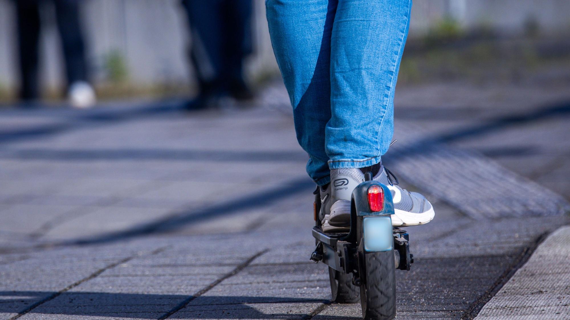 Ein Reisender fährt mit seinem E-Scooter über den Bahnsteig.