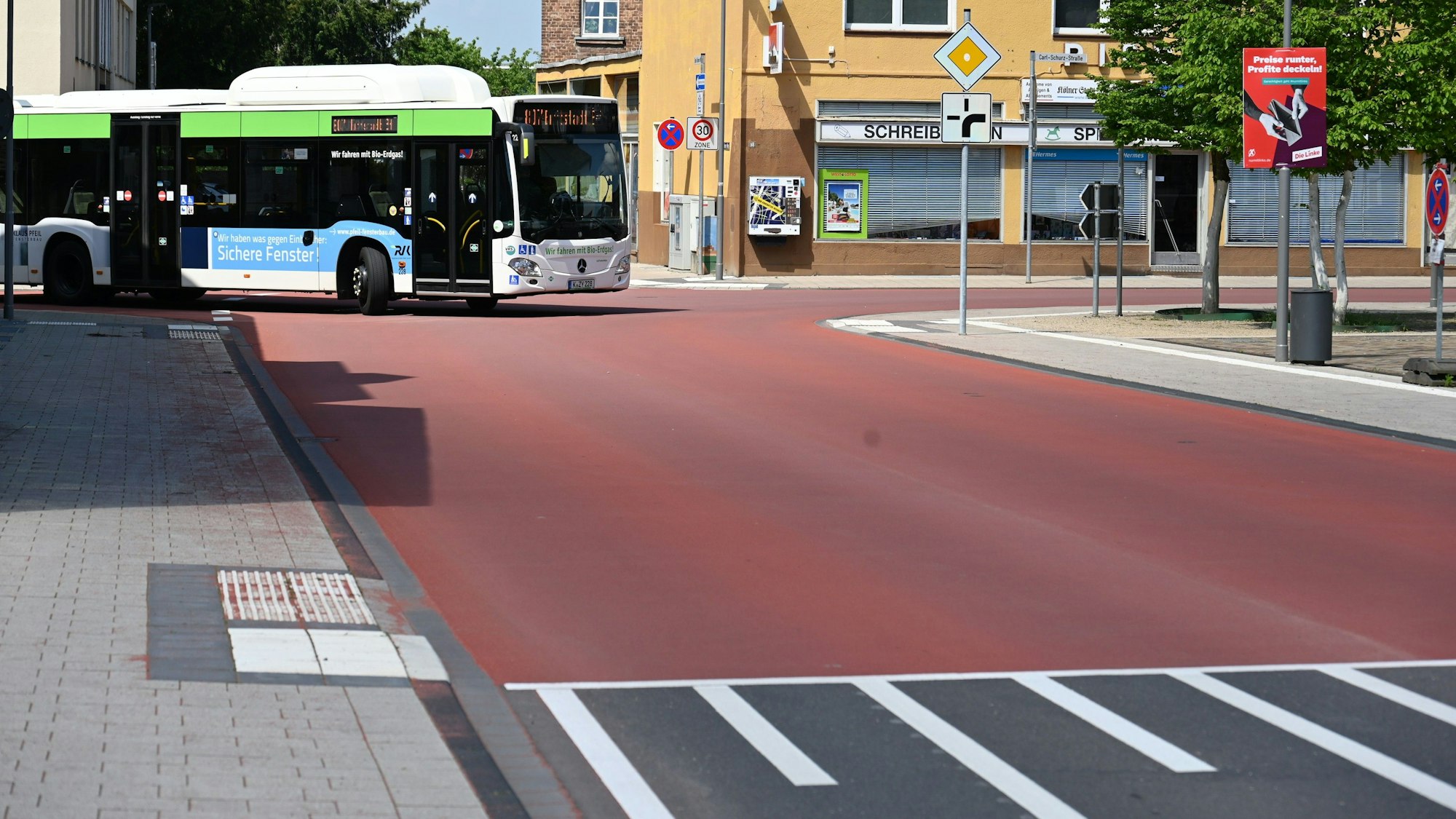 Auf dem Foto ist die Carl-Schurz-Straße in Erftstadt-Liblar zu sehen. Ein Bus fährt um die Ecke. Die gesamte Kreuzung ist mit einem roten Belag versehen.