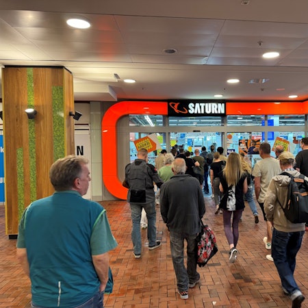 Eine Gruppe von Menschen vor dem Eingang des Saturn-Markts im Einkaufszentrum Hürth-Park.