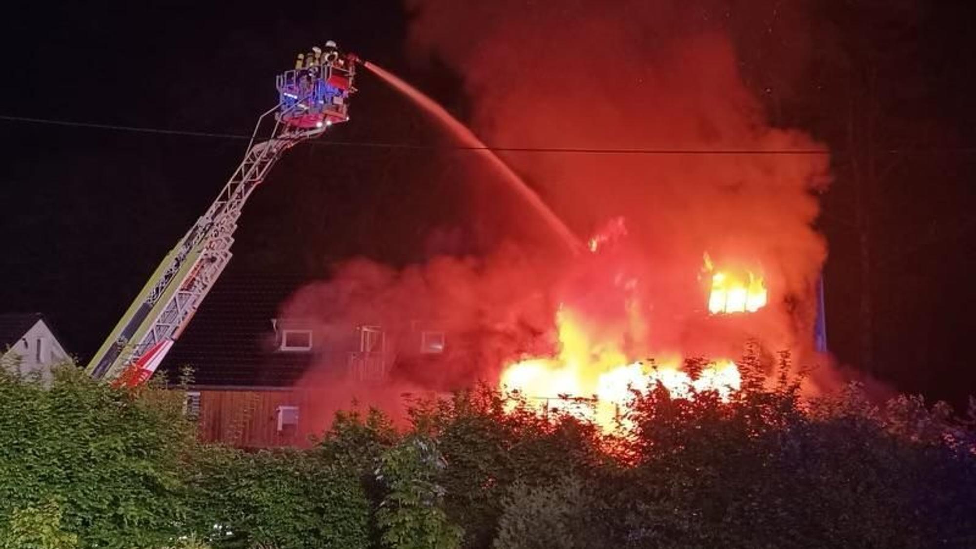 Die Feuerwehr löscht von einer Drehleiter aus ein in Flammen stehendes Haus.