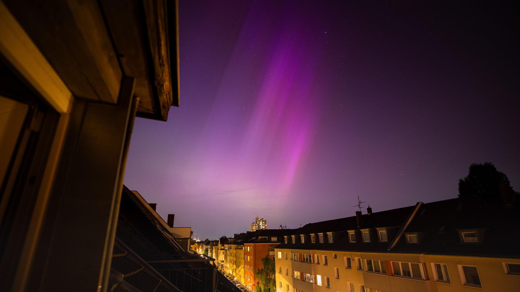 Polarlichter (Aurora Borealis) sind am Nachthimmel über Köln zu sehen. Nach einem starken Sonnensturm ist das Naturphänomen in ganz Europa sichtbar.