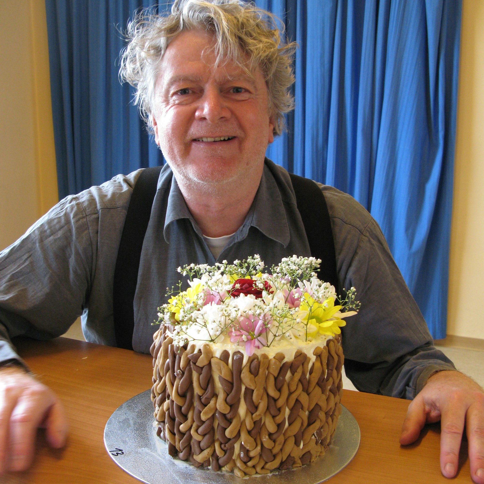 Der Zeitungsreporter mit seiner mit Blumenblüten dekorierten Torte.