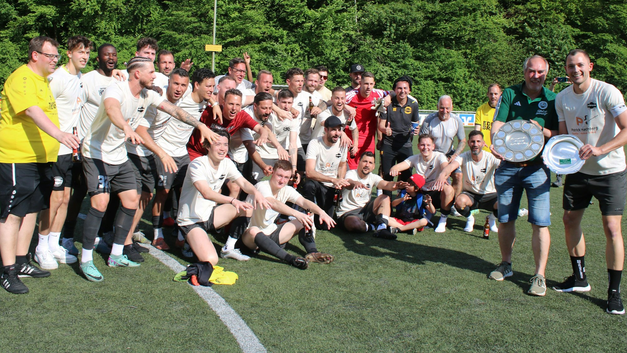 Fußballchef Jürgen Liehn überreicht die Schale an Kapitän Severin Brochhaus. Im Hintergrund jubelt die Mannschaft.