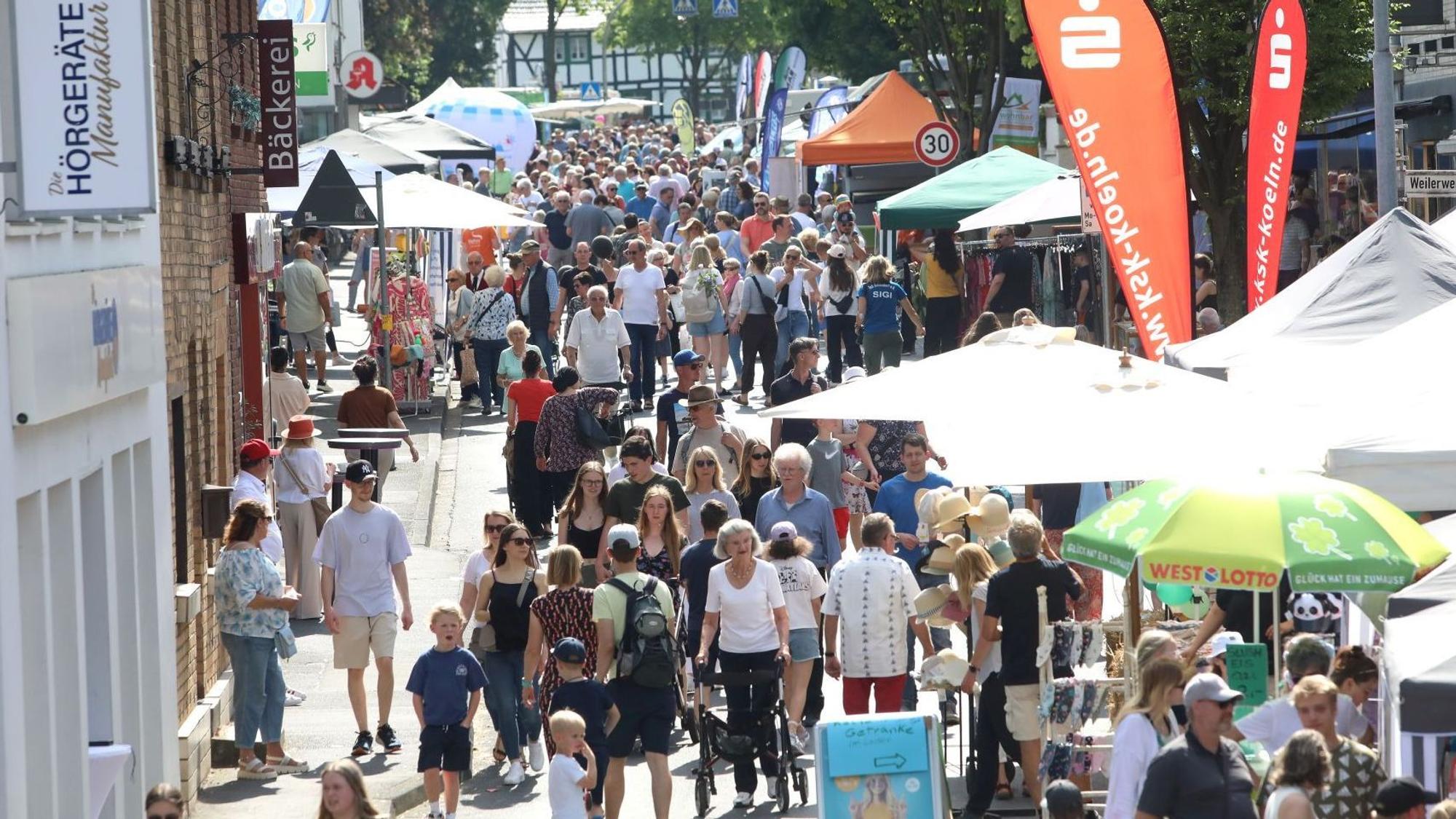 Viele Menschen gehen auf einer für Autos gesperrten Straße an Info-Ständen vorbei.