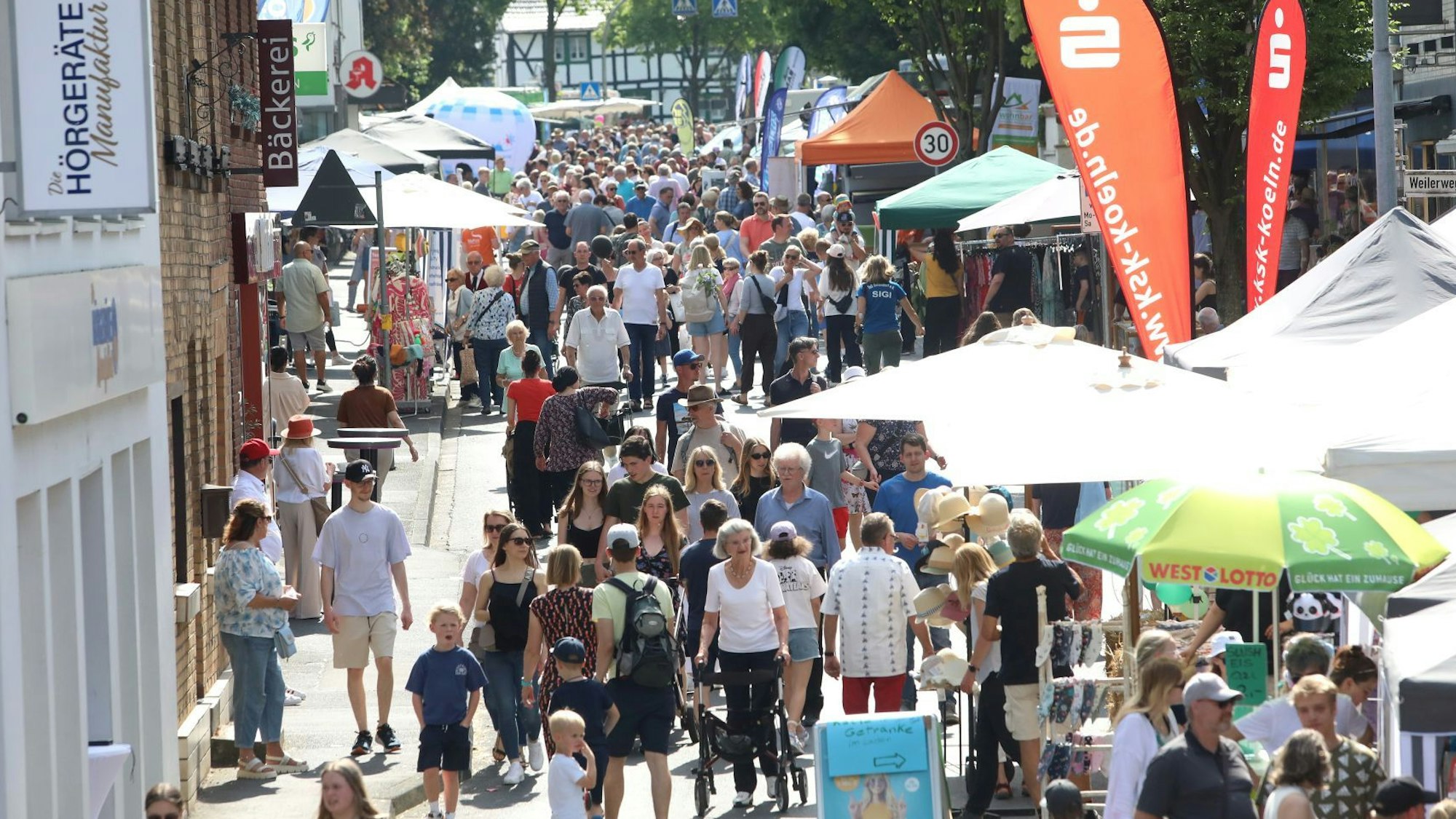 Viele Menschen gehen auf einer für Autos gesperrten Straße an Info-Ständen vorbei.