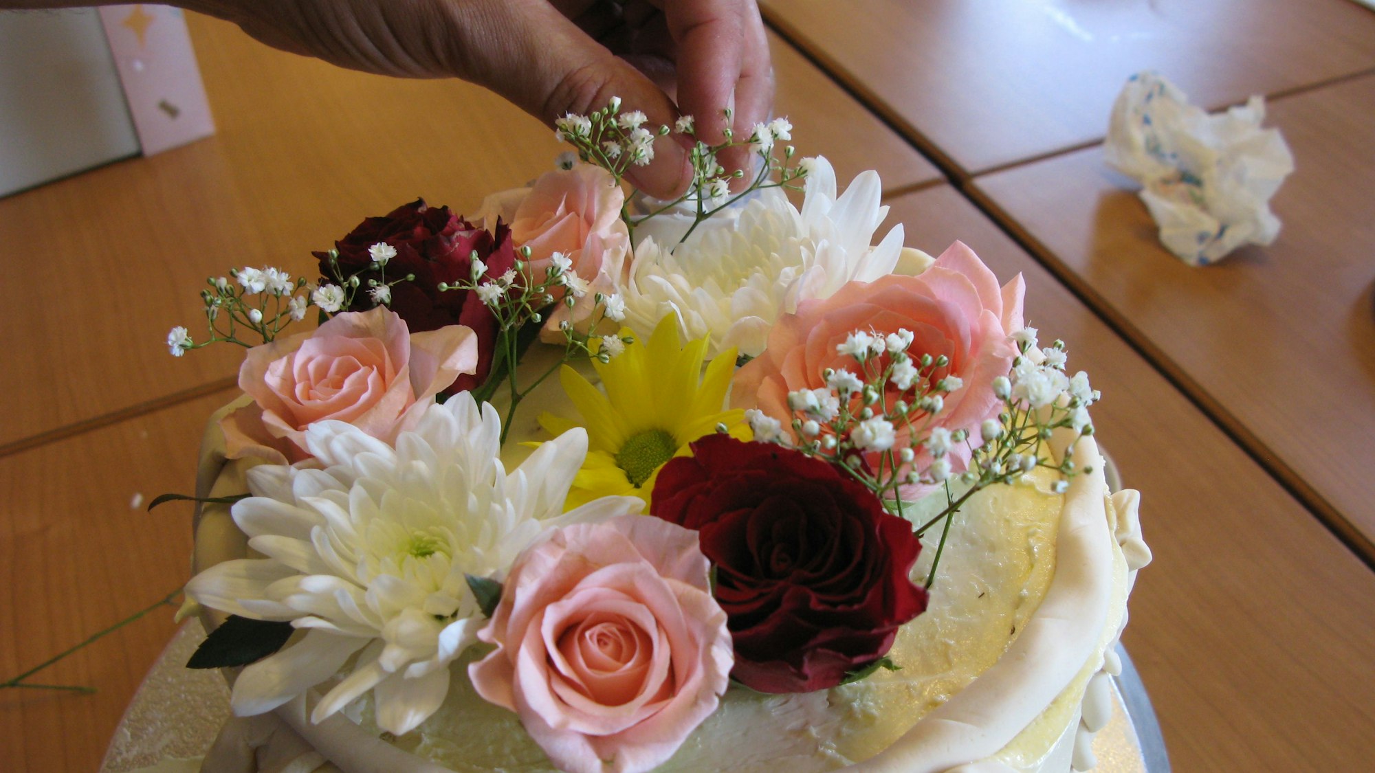 Eine Hand steckt Blüten in die Tortenoberfläche.