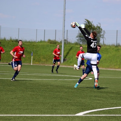 Ein Torwart spielt außerhalb des Strafraums einen Ball mit der Hand.