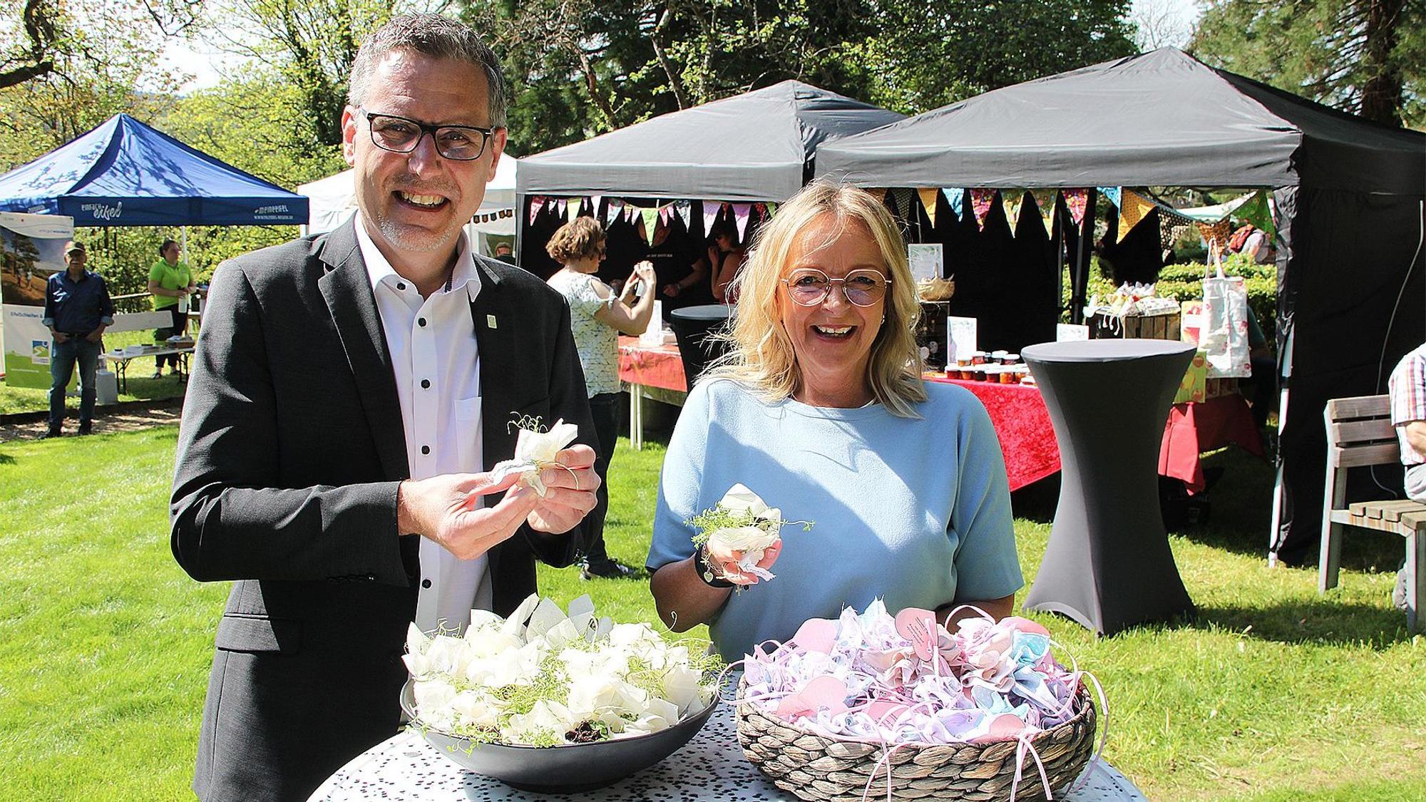 Norbert Crump und Sabine Preiser-Marian stehen vor einem Tisch mit Küchenkräutern in Samenbeuteln.