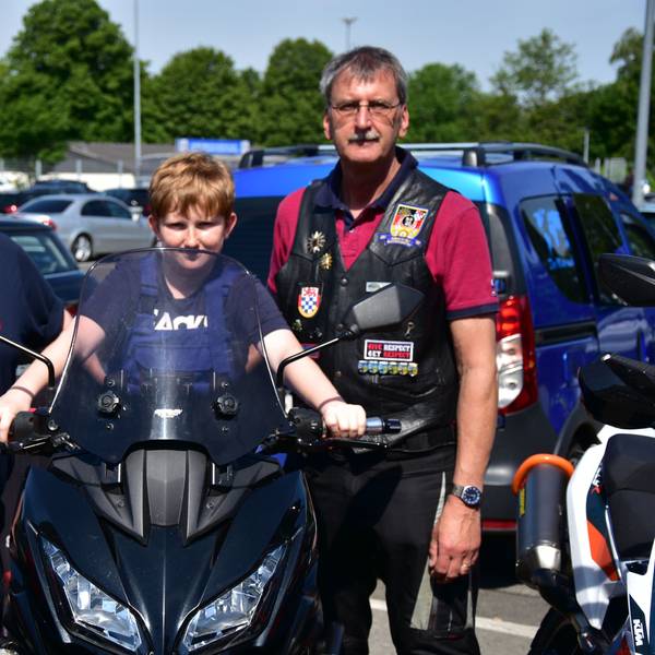 Nachwuchs-Feuerwehrmann Finn sitzt bei der Spendenaktion der Biker der Bundespolizei auf einem Motorrad, eingerahmt von den beiden Bikern Markus Mattern (l.) und Dirk Stenzel (r.).