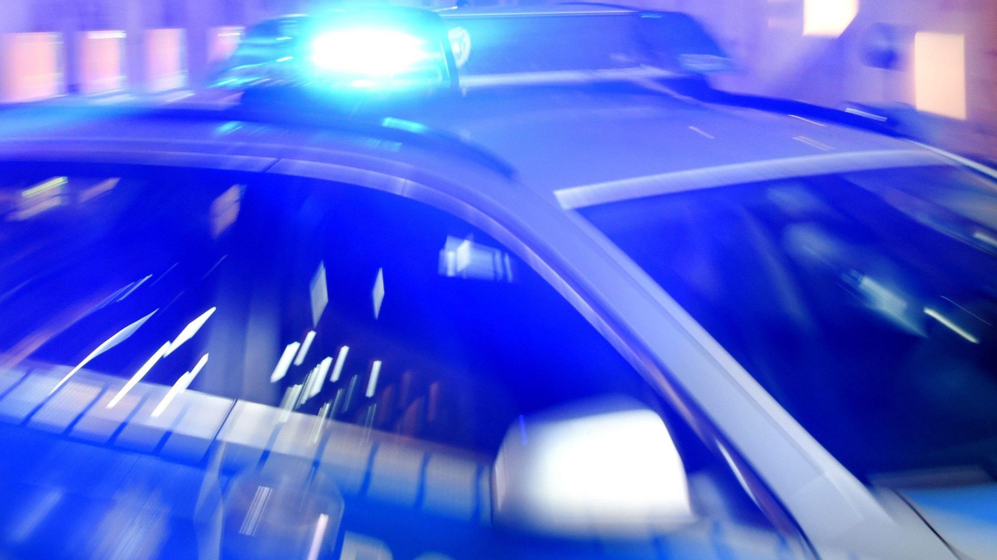 Ein Streifenwagen der Polizei steht mit eingeschaltetem Blaulicht auf der Straße.