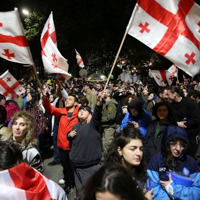 13.05.2024, Georgien, Tiflis: Demonstranten mit georgischen Fahnen nehmen vor dem Parlamentsgebäude an einer Demonstration gegen ein Gesetz teil, das den ausländischen Einfluss auf die Zivilgesellschaft beschneiden soll.