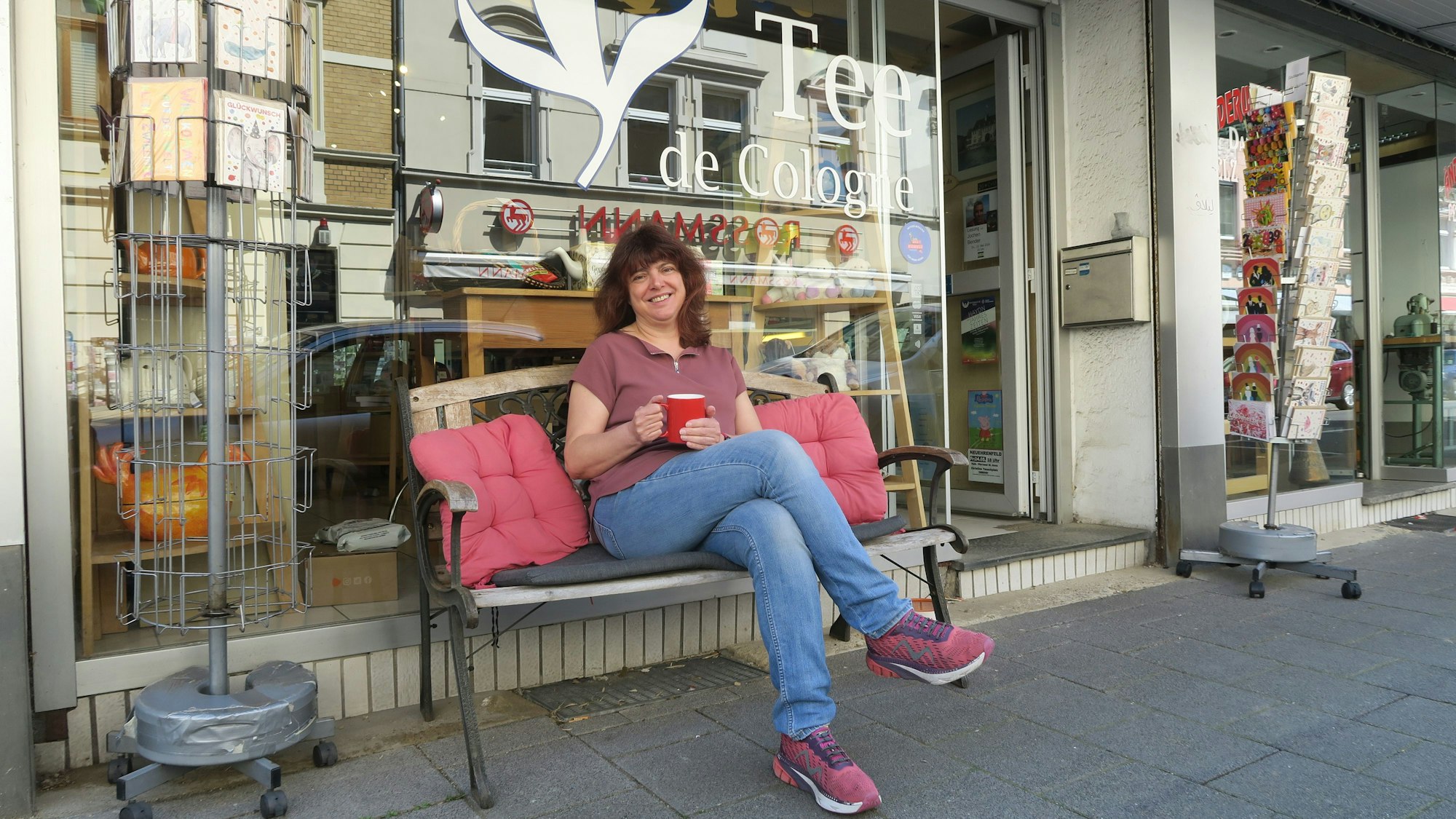 Auf einer Bank sitzt Inhaberin Silvia Legat vor ihrem Laden „Tee de Cologne“. Foto von Hans-Willi Hermans