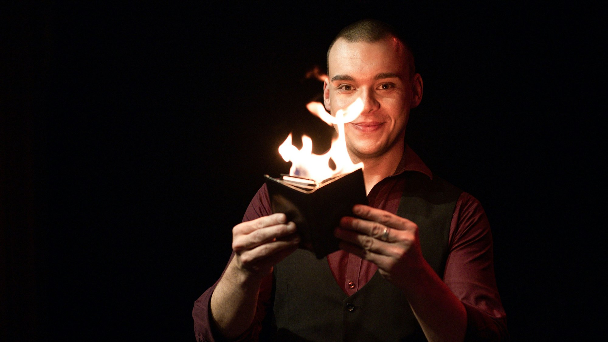 Ein Mann hält ein brennendes Buch.
