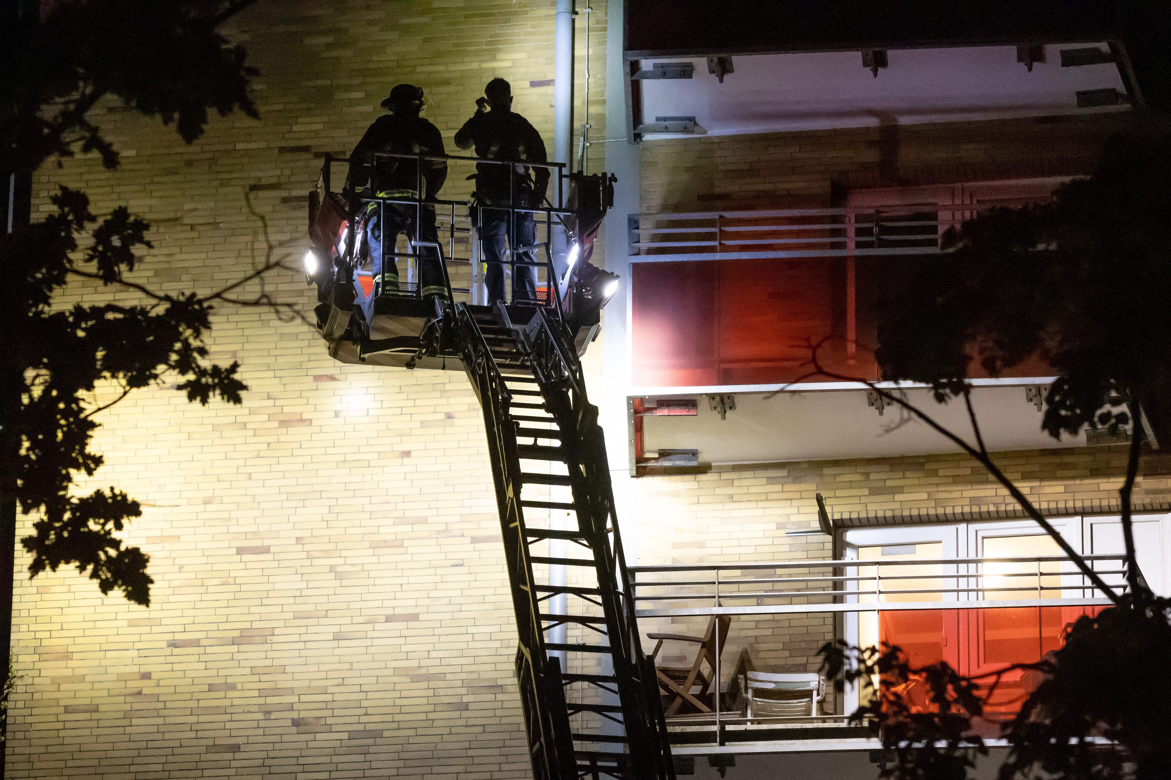 12.05.2024, Hamburg: Einsatzkräfte stehen auf einer Drehleiter an einem Hochhaus im Stadtteil Altona und suchen die Fassade nach Beschädigungen durch Schüsse ab.