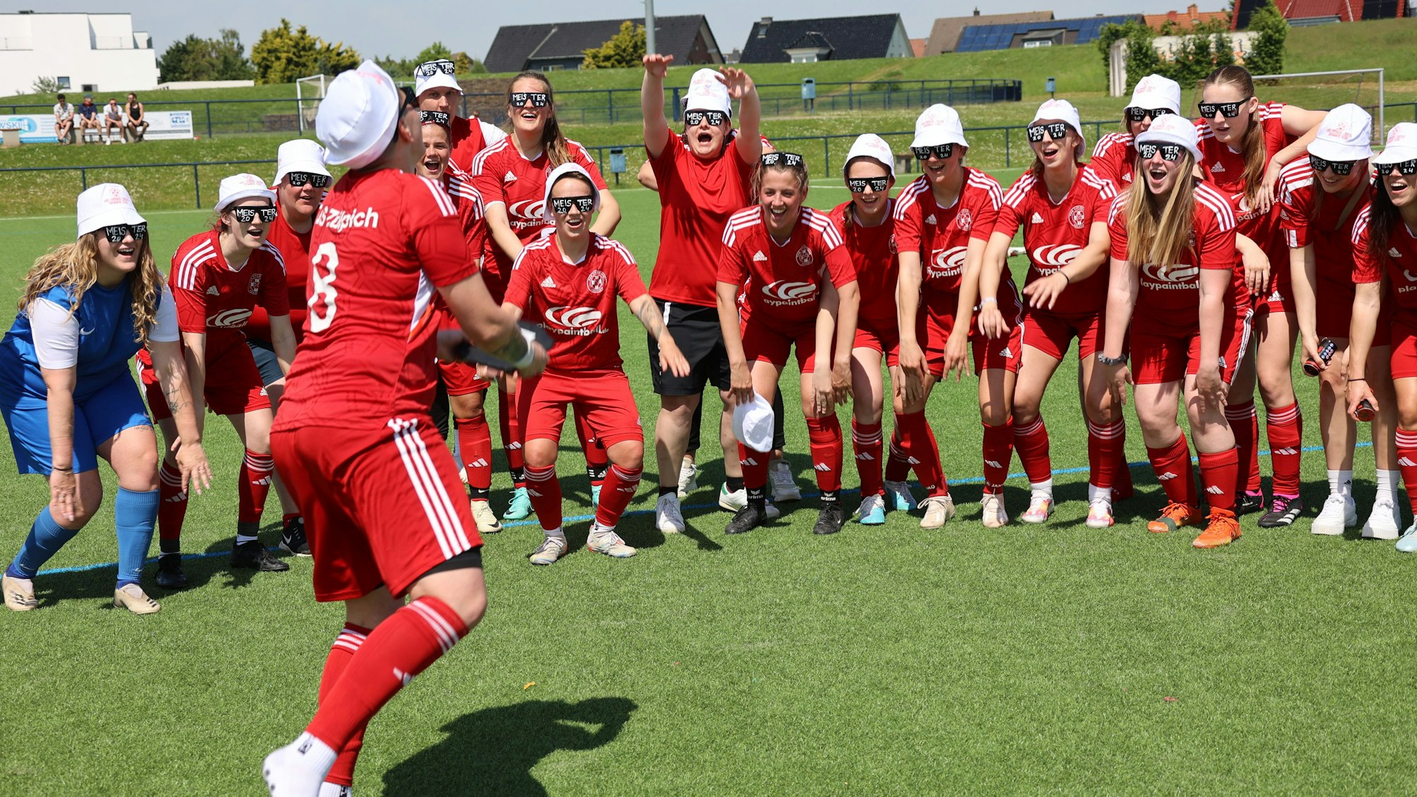 Fußballspielerinnen tragen weiße Kappen und jubeln.