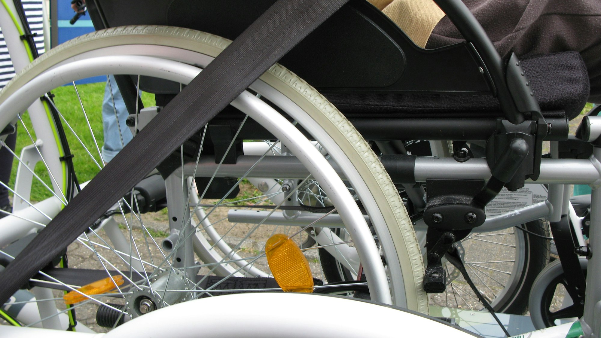 Ein Gurt zur Sicherung des Rollstuhls auf der Rikscha-Plattform ist über das Rollstuhlrad gespannt.