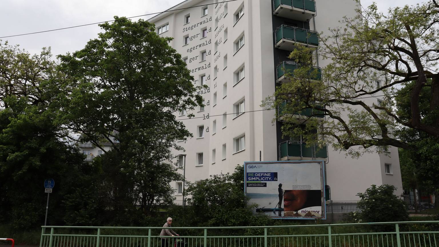Ein weißes Hochhaus mit grün gestrichenen Balkonen, umgeben von Bäumen, in Mülheims Stegerwaldsiedlung. Foto von Uwe Schäfer