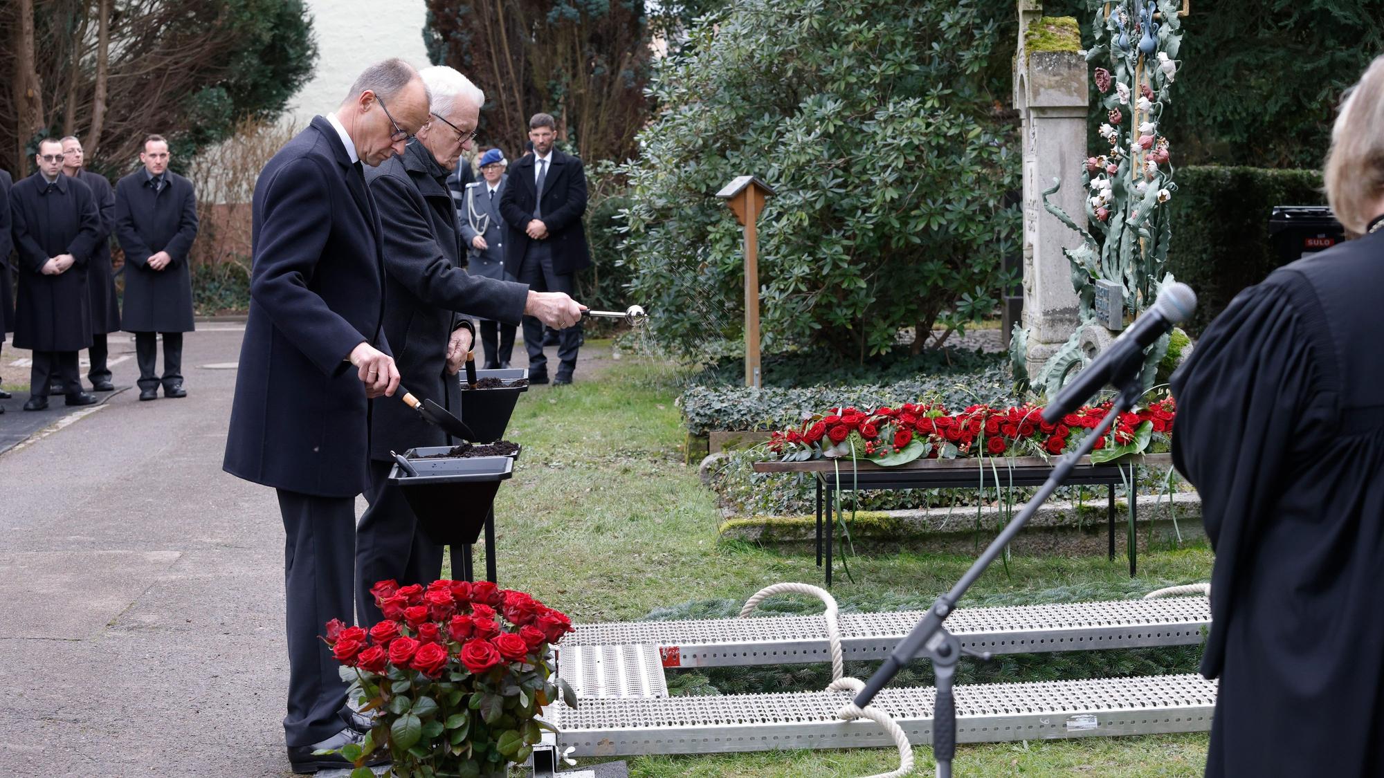 Nach dem Gottesdienst bei der Trauerfeier für Wolfgang Schäuble stehen Winfried Kretschmann (Bündnis 90/Die Grünen, r), Ministerpräsident von Baden-Württemberg, und Friedrich Merz (l), Bundesvorsitzender der CDU, am Grab auf dem Friedhof.