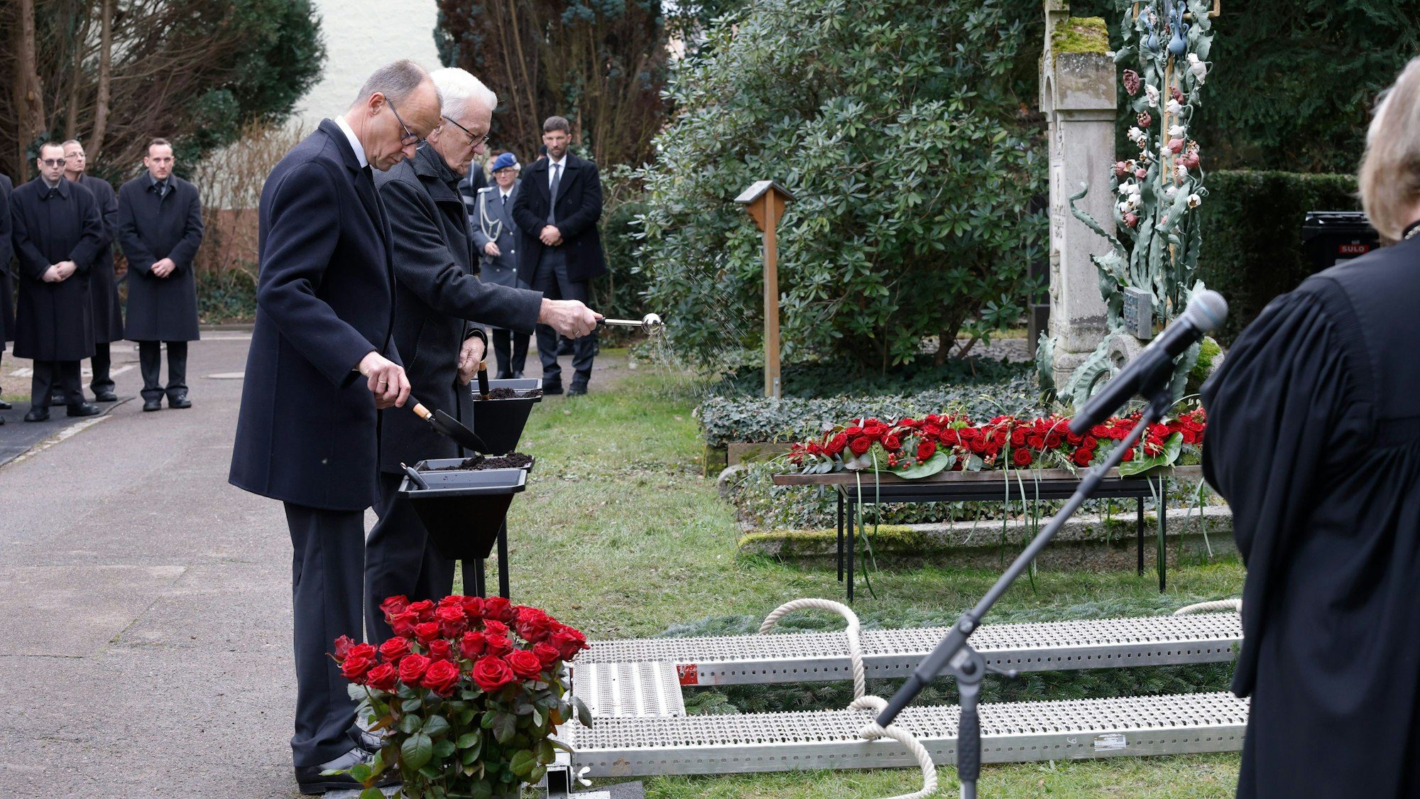 Nach dem Gottesdienst bei der Trauerfeier für Wolfgang Schäuble stehen Winfried Kretschmann (Bündnis 90/Die Grünen, r), Ministerpräsident von Baden-Württemberg, und Friedrich Merz (l), Bundesvorsitzender der CDU, am Grab auf dem Friedhof.