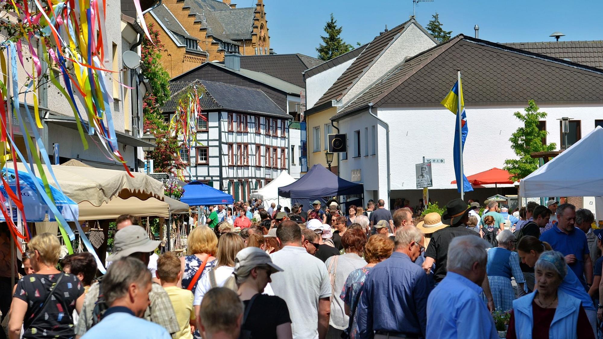 Viele Menschen drängen sich zwischen Marktständen und Fachwerkhäusern.