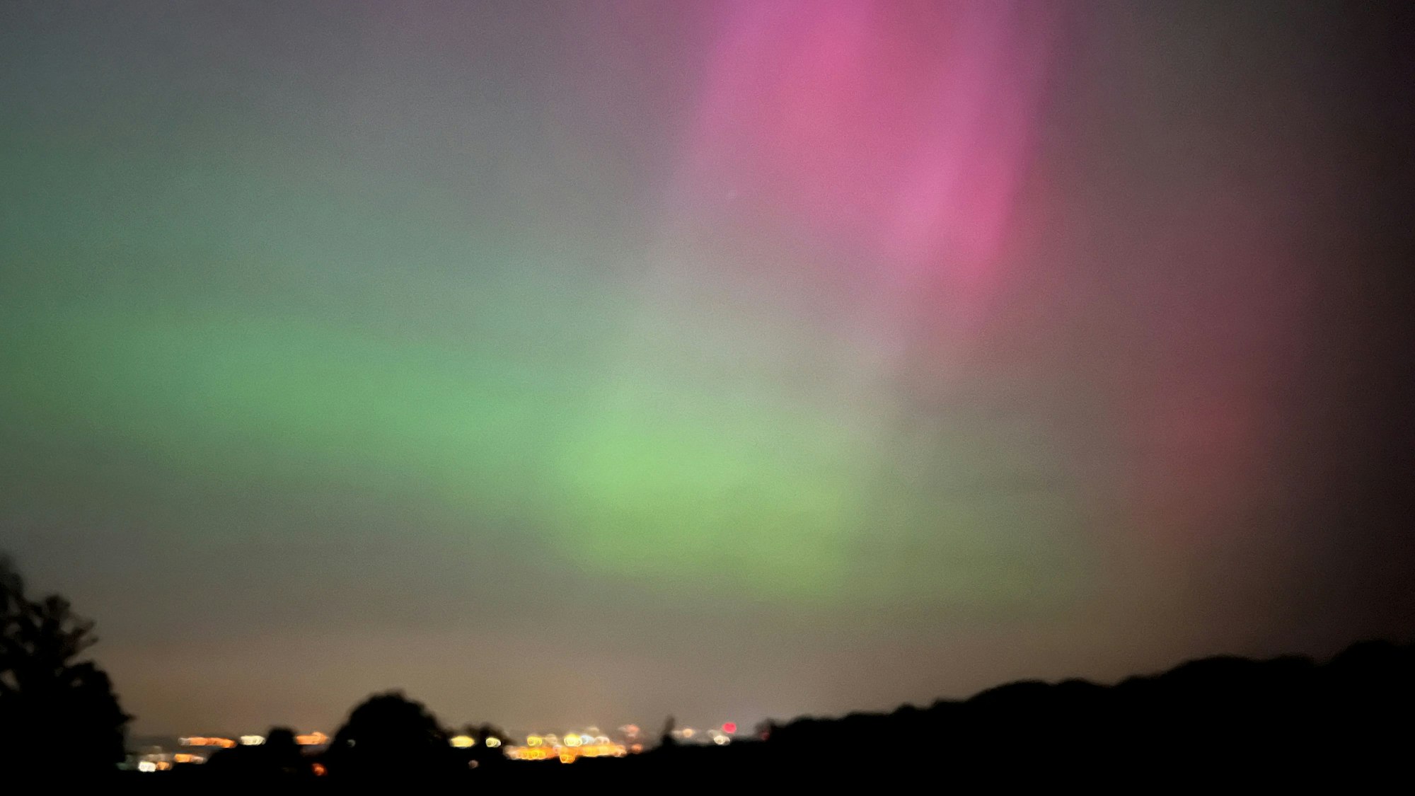 Über der Stadt schillert der Himmel grün und rot.