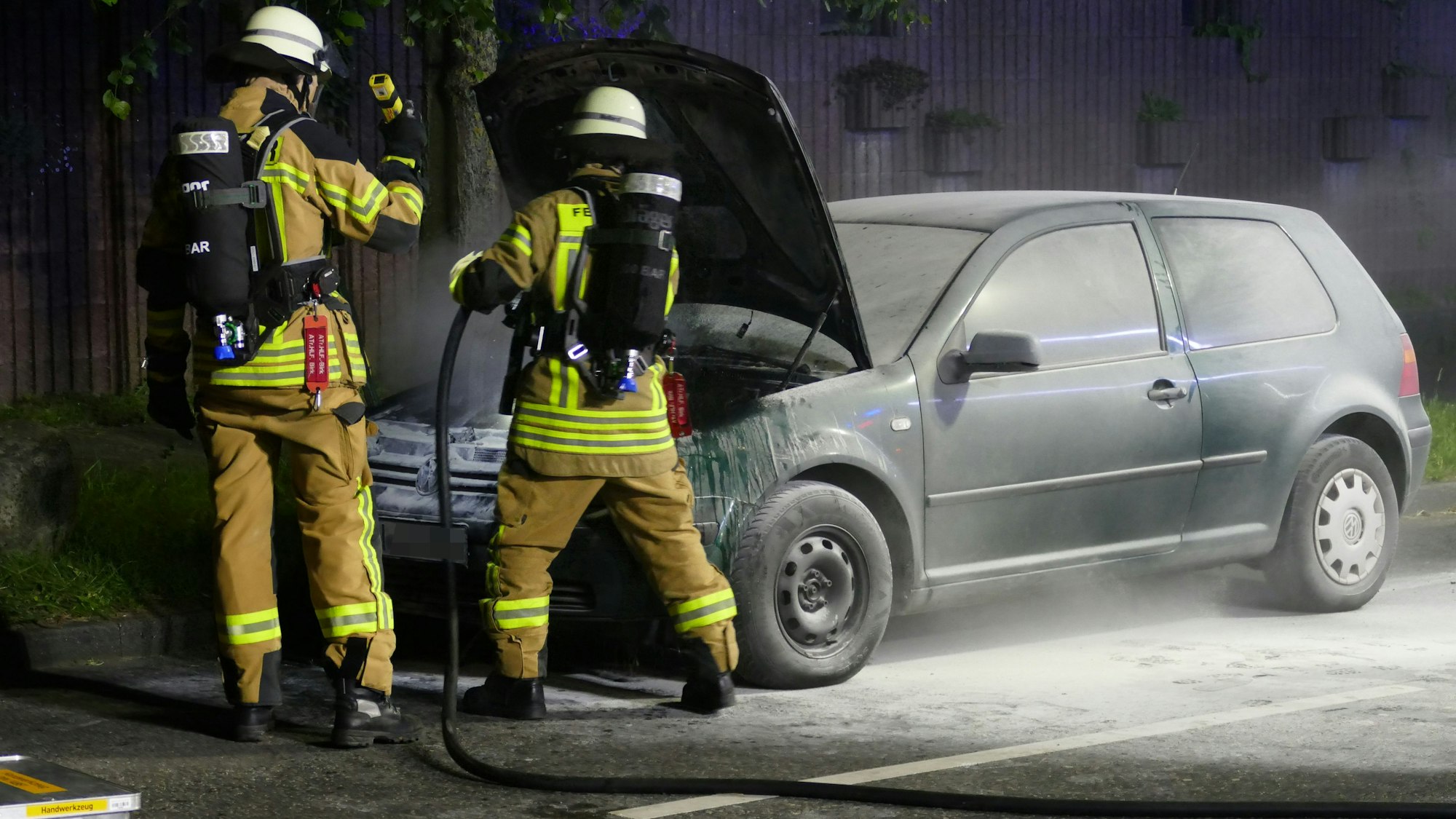 Feuerwehrleute löschen mit einem Schnellangriffsschlauch nach.