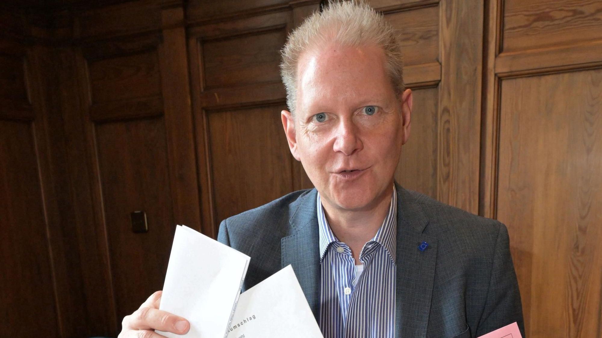 Der Wahlleiter mit Stimmzetteln in der Hand.