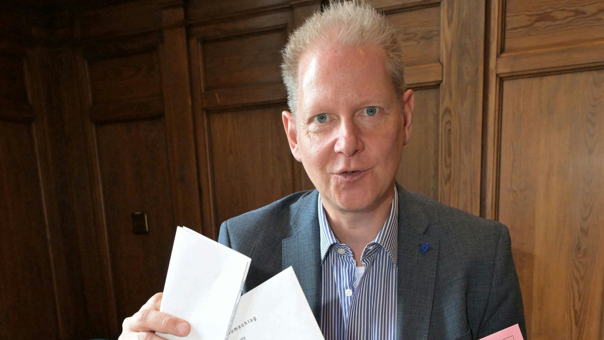 Der Wahlleiter mit Stimmzetteln in der Hand.