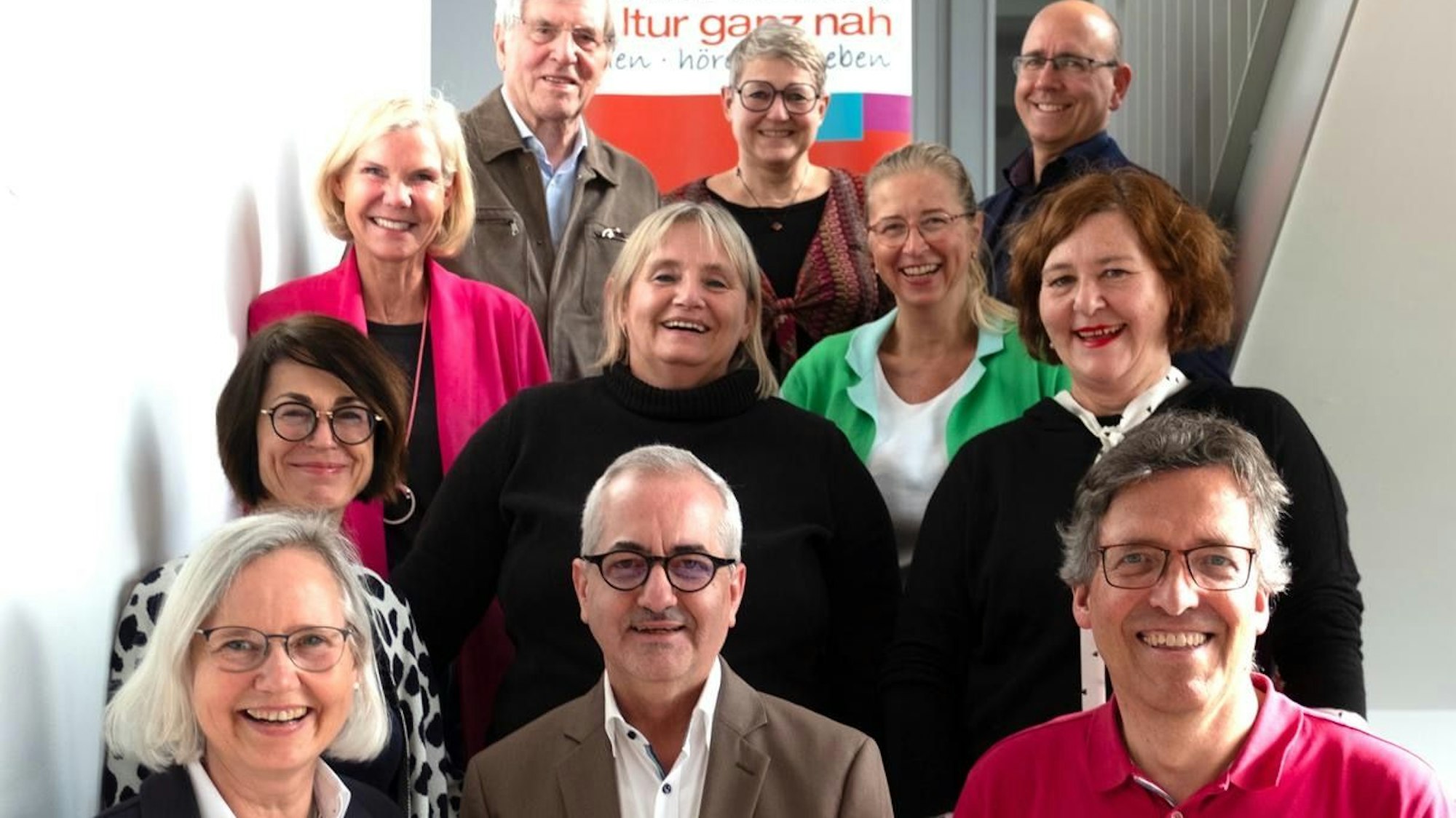 Frauen und Männer stehen auf einer Treppe.