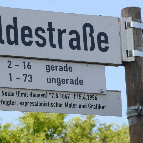 Das Bild zeigt ein Straßenschild mit der Aufschrift Noldestraße und einem Info-Hinweis darunter.