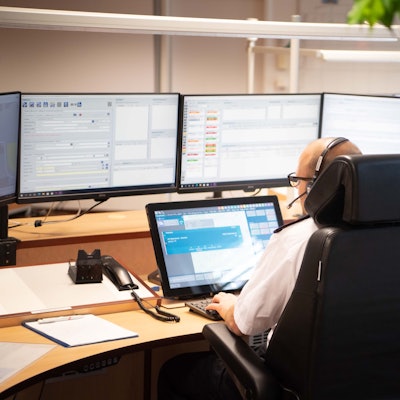 Das Bild zeigt einen Disponenten in der Leitstelle, der vor zahlreichen Monitoren sitzt.