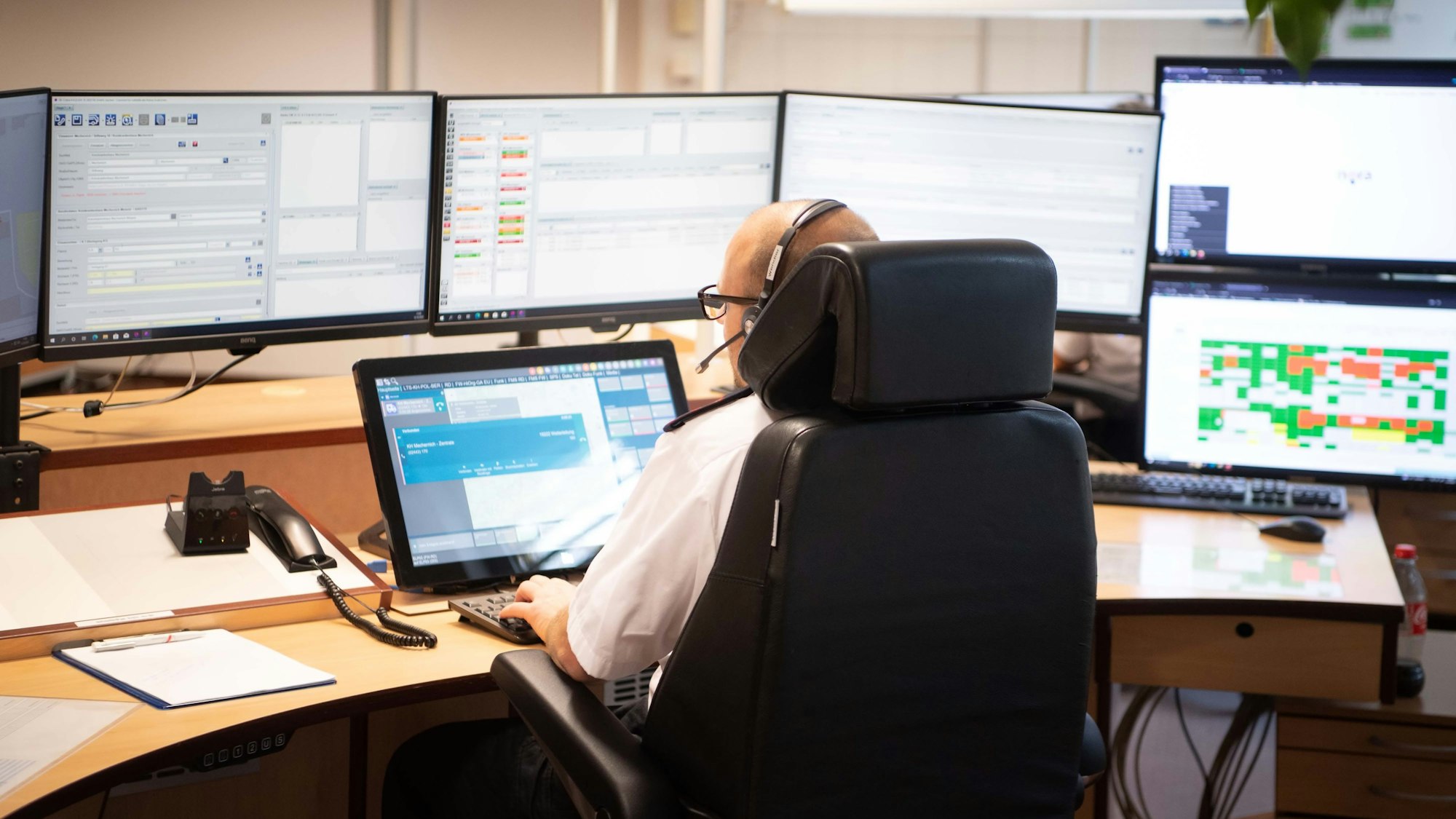Ein Leitstellen-Disponent sitzt vor sieben Bildschirmen.