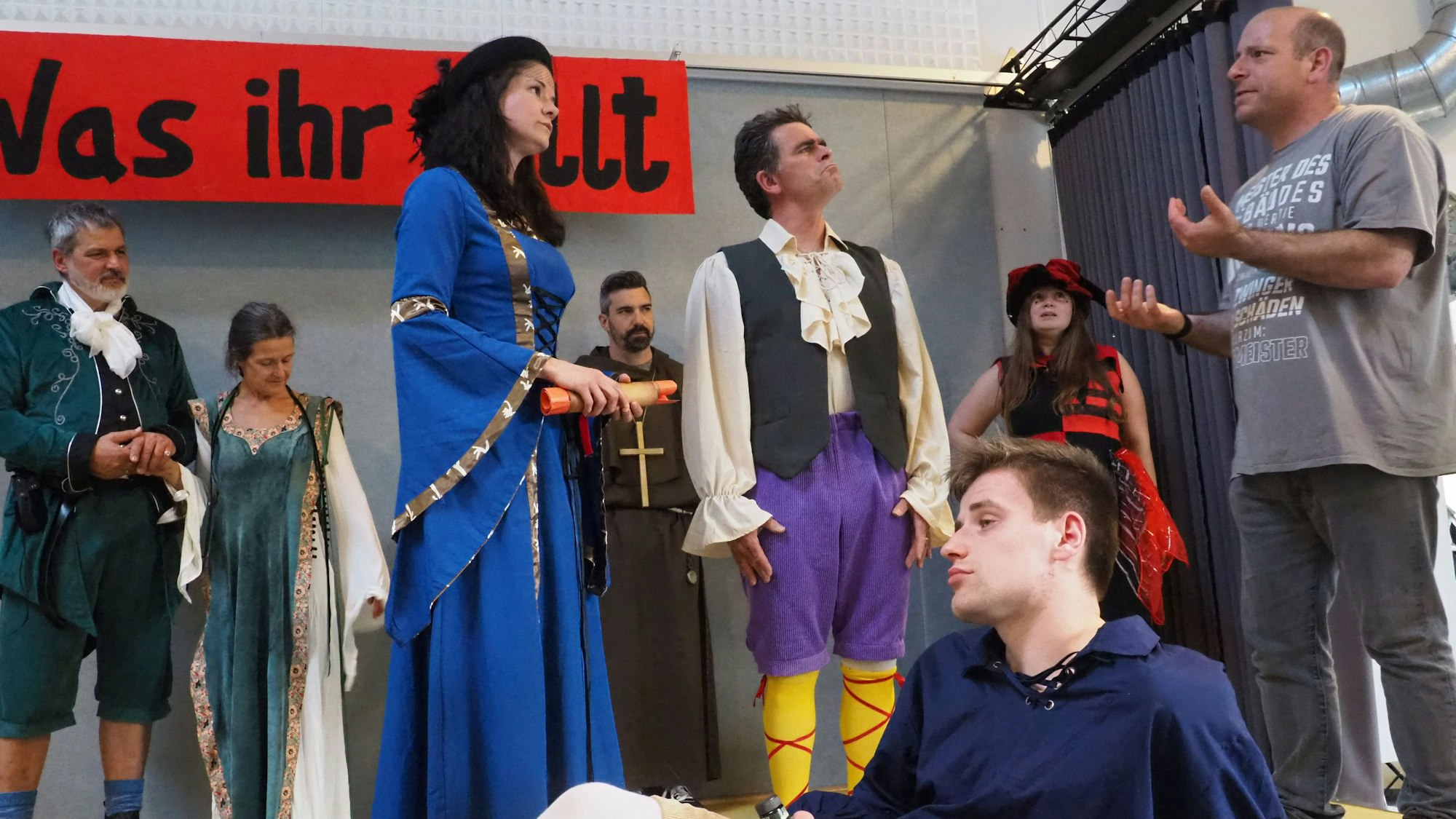 Jonas Kuley sitzt im Vordergrund, dahinter agieren mehrere Schauspieler.