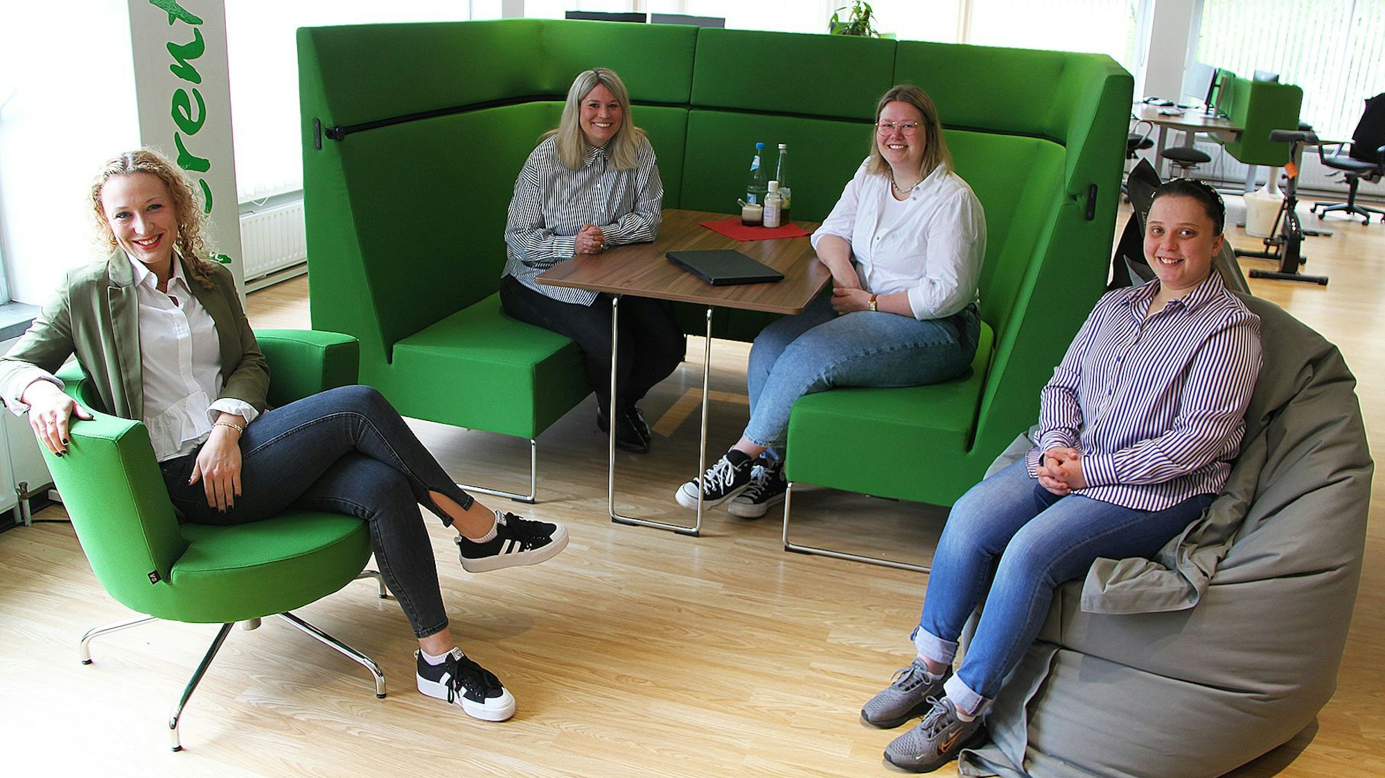 Linda Heinen, Jennifer Meuren und Katharina Hellendahl sitzen auf grünen Sitzmöbeln zusammen, Jona Verbojshi daneben auf einem grauen Sitzsack.