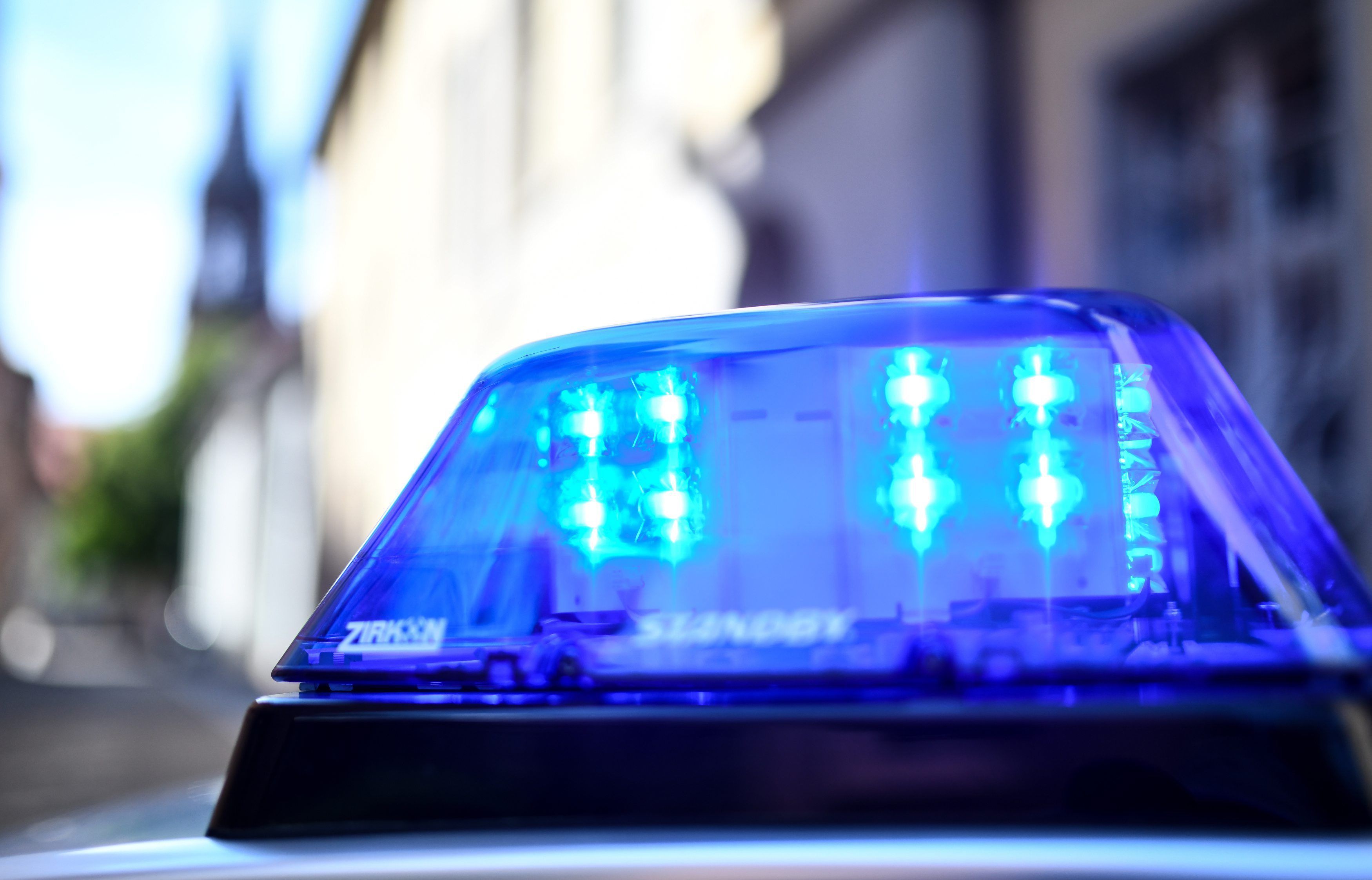 Ein Polizeiauto mit blinkendem Blaulicht steht vor einem Gebäude.