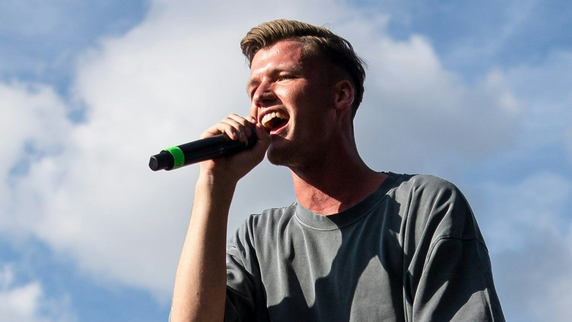 Julian Sommer steht auf der Bühne und hält ein Mikrofon in der Hand.