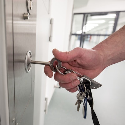 Das Bild zeigt einen Justizbeamten, der eine Zellentüre aufschließt.