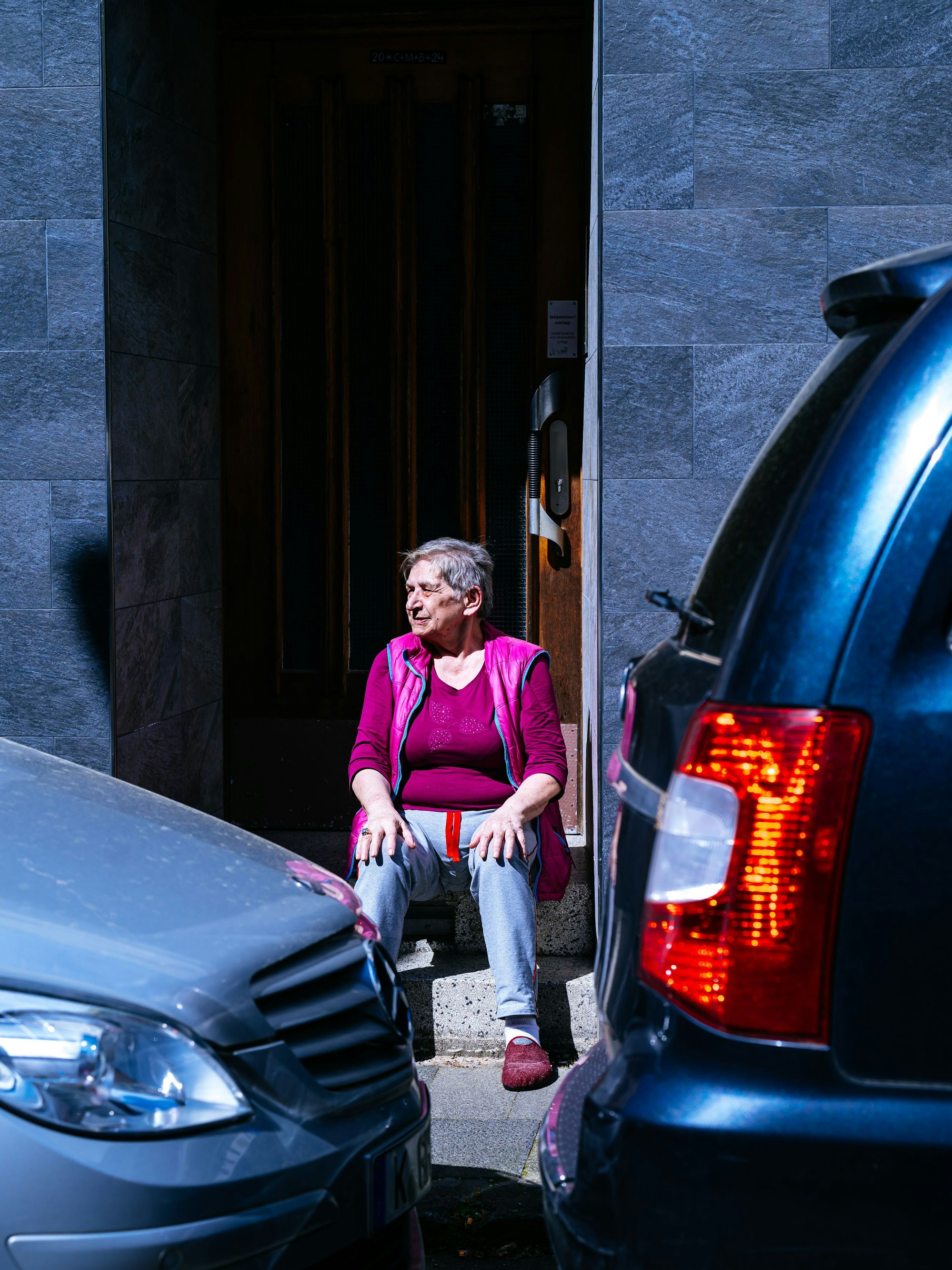Eine Anwohnerin schaut zwischen den Stoßstangen auf die Straße.