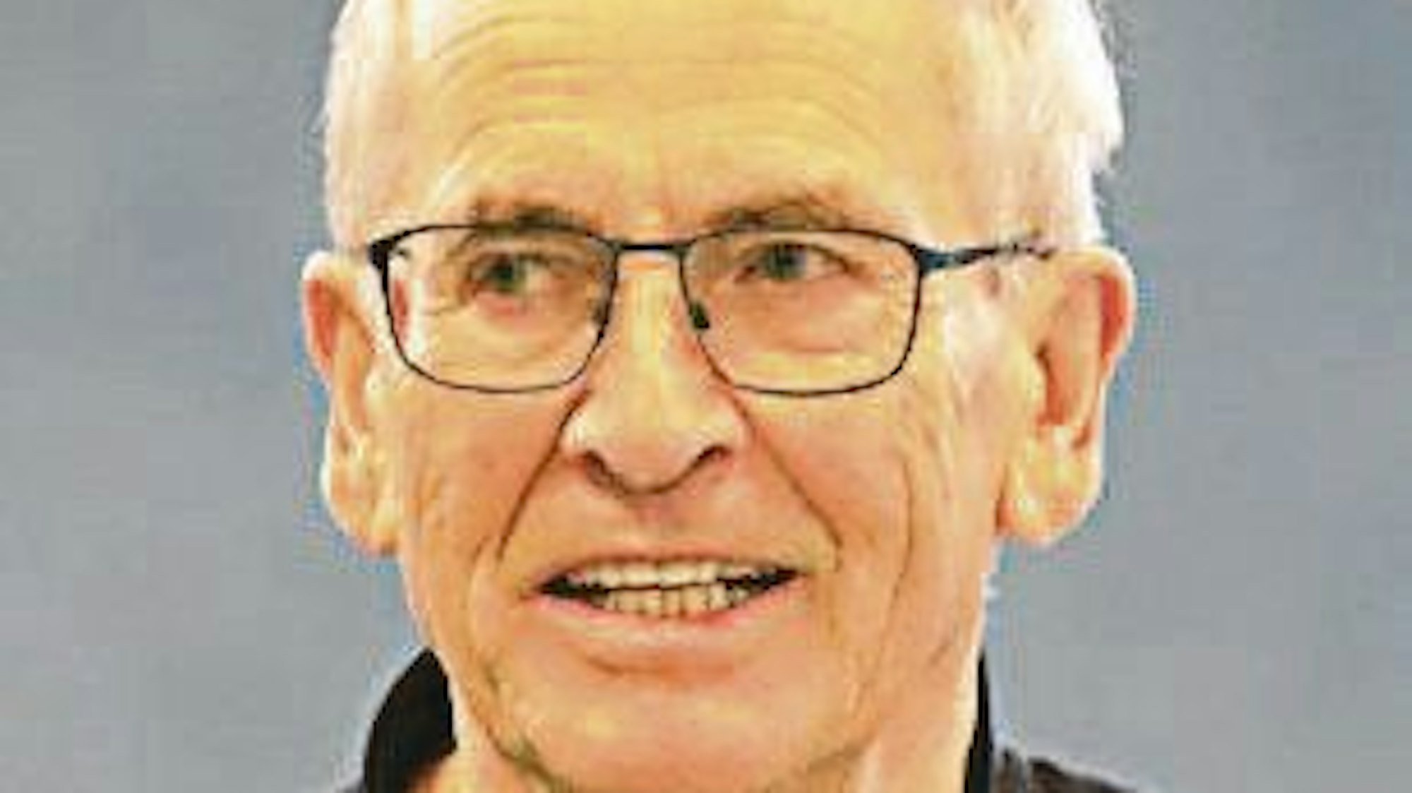 Ein Mann mit weißen Haaren und einer dünnrandigen schwarzen Brille.