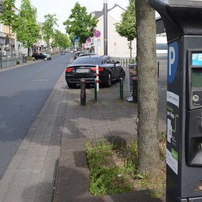 Parkscheinautomat an einer Straße. An der Seite ein weißes P auf blauem Grund, an der Front ein LCD-Display und farbige Knöpfe.