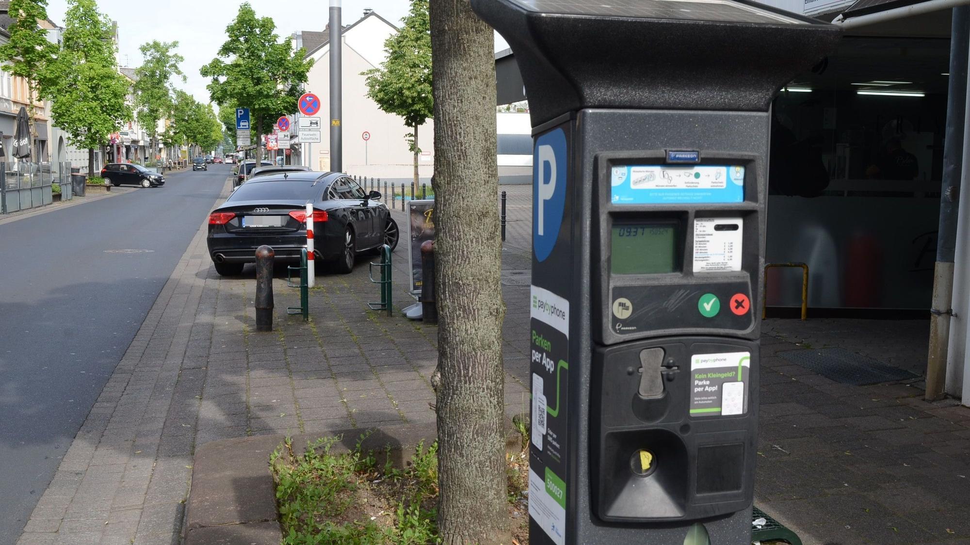 Parkscheinautomat an einer Straße. An der Seite ein weißes P auf blauem Grund, an der Front ein LCD-Display und farbige Knöpfe.