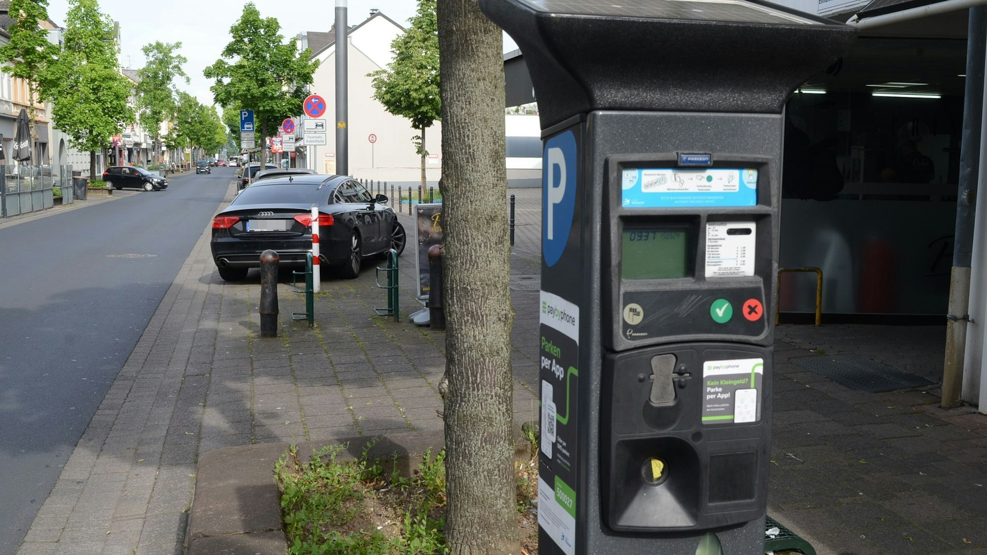 Parkscheinautomat an einer Straße. An der Seite ein weißes P auf blauem Grund, an der Front ein LCD-Display und farbige Knöpfe.